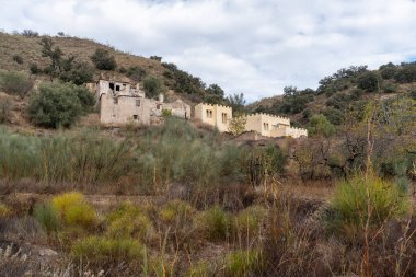 İspanya 'nın güneyinde Granada' da eski bir kır evinde ağaçlar ve çalılar var, gökyüzü bulutlu.