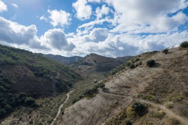 Granada 'nın güneyindeki dağda bir vadi, eski bir kır evi var, ağaçlar ve çalılar var, gökyüzünde bulutlar var