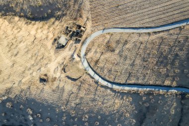 Granada 'nın güneyinde bir yolun ve bir çiftlik alanının havadan çekilmiş fotoğrafı. Harabelerde eski bir kır evi var, mahsul badem ağaçları.