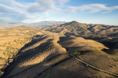 Granada 'nın güneyindeki dağlık bölgede badem mahsulleri var, gökyüzünde bulutlar var.