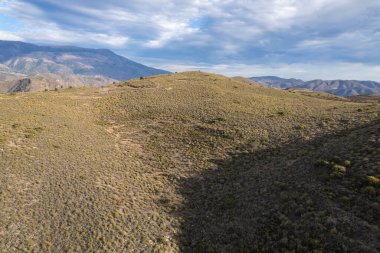 İspanya 'nın güneyindeki dağlık arazide çam ağaçları ve çalılardan oluşan bir orman var. Gökyüzünde bulutlar var.