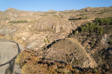İspanya 'nın güneyindeki dağlık arazide bir nehir var, ağaçlar ve kayalar var, gökyüzü açık.