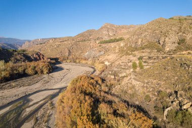 İspanya 'nın güneyindeki dağlık arazide bir nehir var, ağaçlar ve kayalar var, gökyüzü açık.