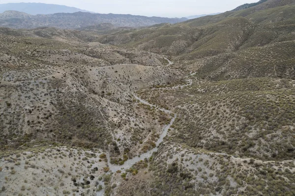 Almerya 'daki Tabernas Çölü' nün kurak manzarası (İspanya), dağlık bir manzara, çalılar var ve gökyüzü bulutlu.