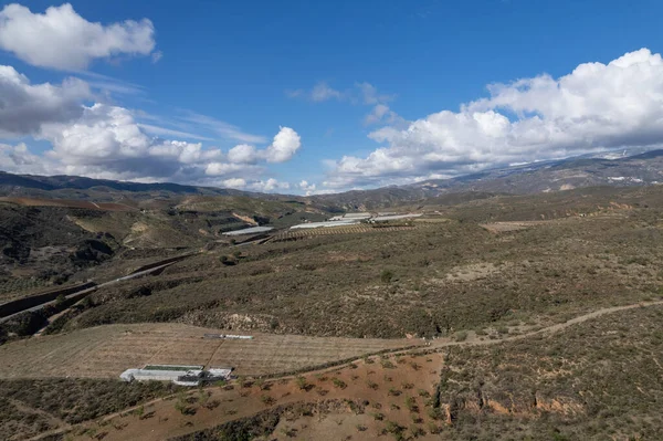 Endülüs 'ün güneyindeki dağlık bölgede birkaç sera var, çalılar ve ağaçlar var, gökyüzünde bulutlar var.
