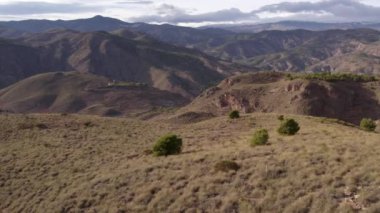 İspanya 'nın güneyindeki dağlık arazi, ağaçlar ve çalılar var, kurak bir bölge, gökyüzünde bulutlar var.