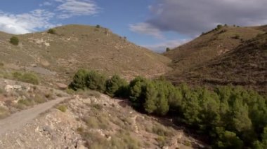 İspanya 'nın güneyindeki dağlık arazi, ağaçlar ve çalılar var, kurak bir bölge, gökyüzünde bulutlar var.