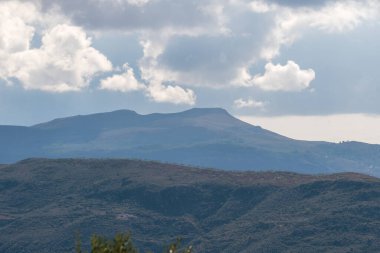 Endülüs 'ün güneyindeki dağlık bölgede ağaçlar ve çalılar var, gökyüzünde bulutlar var.