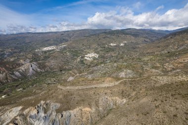 Sierra Nevada 'nın yamaçlarında birkaç kasaba, dağlık bir bölge, çalılar ve ağaçlar var, gökyüzünde bulutlar var.