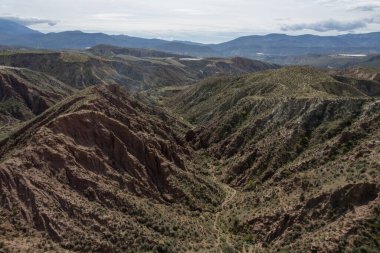 Endülüs 'ün güneyindeki dağlık bölgede ağaçlar, çalılar, vadiler, gökyüzünde bulutlar var.