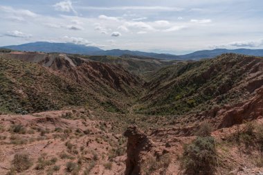Endülüs 'ün güneyindeki dağlık bölgede ağaçlar, çalılar, vadiler, gökyüzünde bulutlar var.