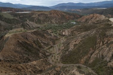 Endülüs 'ün güneyindeki dağlık bölgede ağaçlar, çalılar, vadiler, gökyüzünde bulutlar var.