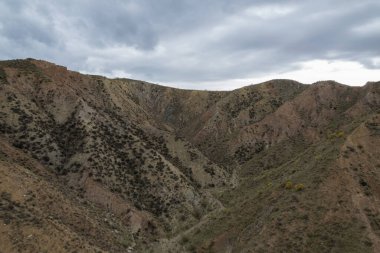 Endülüs 'ün güneyindeki dağlık bölgede ağaçlar, çalılar, vadiler, gökyüzünde bulutlar var.