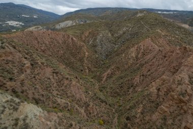 Endülüs 'ün güneyindeki dağlık bölgede ağaçlar, çalılar, vadiler, gökyüzünde bulutlar var.