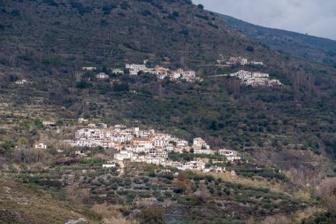 Sierra Nevada 'nın yamaçlarında iki köy var, zeytin ağaçları var, çalılar var, gökyüzünde bulutlar var