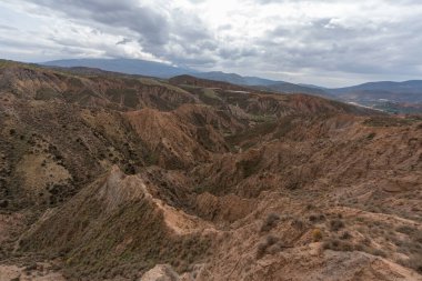 Endülüs 'ün güneyindeki dağlık bölgede çalılar, vadiler ve kurak bir bölge var. Gökyüzünde bulutlar var.
