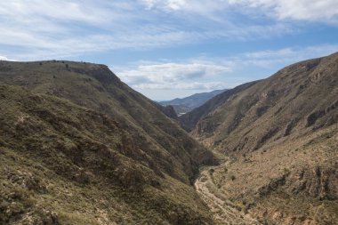 İspanya 'nın güneyindeki dağlık arazi, çalılar var, arazi dik, gökyüzünde bulutlar var.