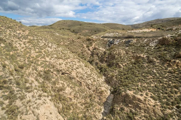İspanya 'nın güneyindeki dağlık arazi, çalılar var, arazi dik, gökyüzünde bulutlar var.