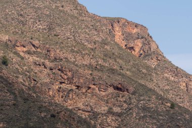 İspanya 'nın güneyindeki sarp arazi, kayalık duvarlar ve oyukları var, yamaçlarında çalılar var, gökyüzü açık.