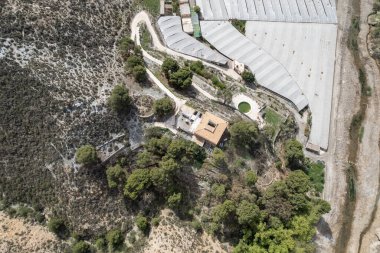 Birkaç seranın ve evin havadan çekilmiş fotoğrafı. Yüzme havuzu, ağaçlar ve çalılar var.