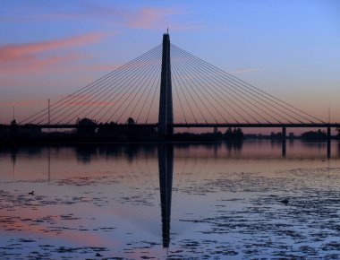Gün batımında nehirde köprü.