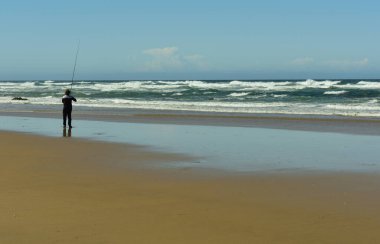 Kimliği belirlenemeyen yalnız bir balıkçı Hindistan Okyanusu 'na uzanan kuyruğuyla sabırla sahilde bekliyor.