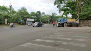 Zebra inşaat halindeki bir yolun yanından geçiyor, yol bakımında trafik var.
