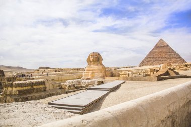 Mısır 'ın Giza şehrinde firavunların, Cheops' ların, Khafren 'lerin ve Mikerin' in piramitlerinin arka planına karşı büyük sfenks.