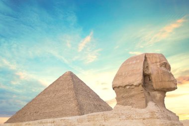 Mısır 'ın Giza şehrinde firavunların, Cheops' ların, Khafren 'lerin ve Mikerin' in piramitlerinin arka planına karşı büyük sfenks.