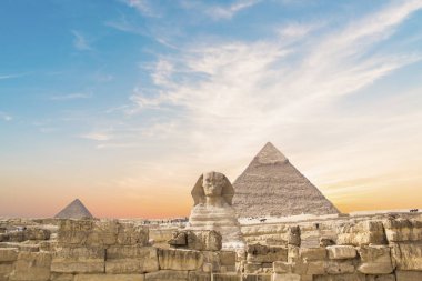 Mısır 'ın Giza şehrinde firavunların, Cheops' ların, Khafren 'lerin ve Mikerin' in piramitlerinin arka planına karşı büyük sfenks.