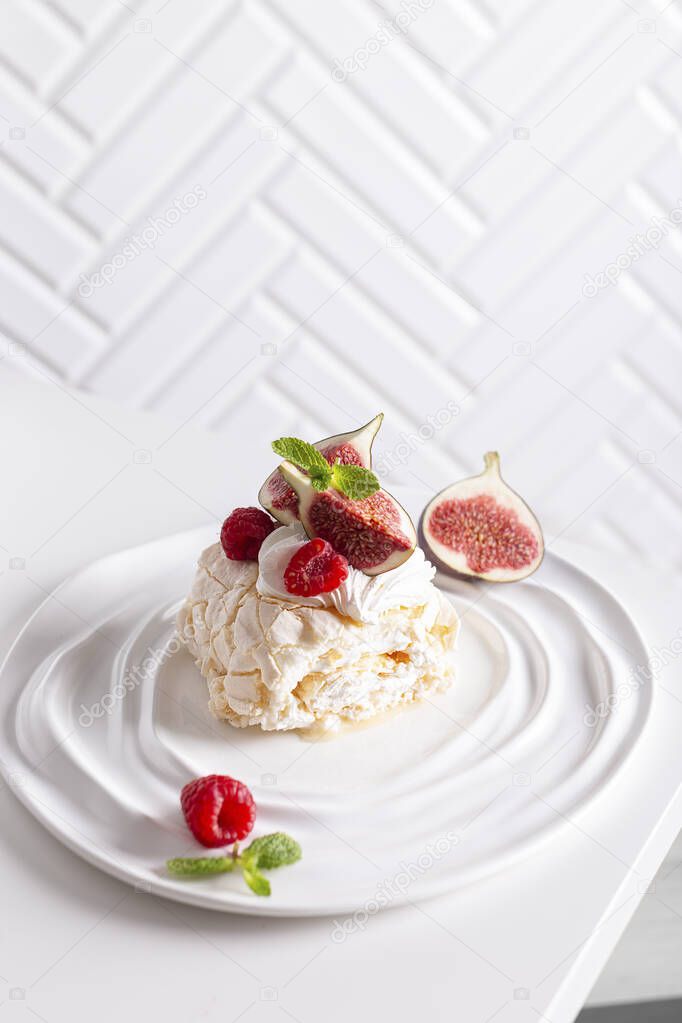 Pavlova dessert, piece of meringue roll decorated with berries and figs