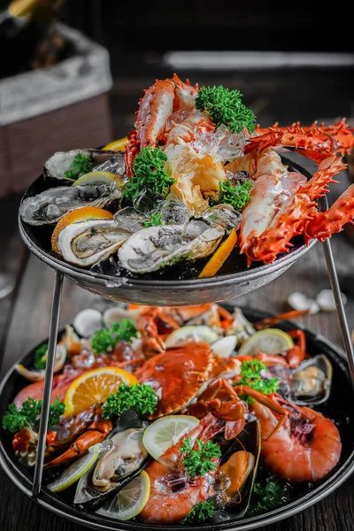 2-Tier Seafood Platter. Platters of prawns, oysters, crabs and king crab on ice, garnished with lime and lemon to taste. Close-up. Rustic style. Gourmet meal. French cuisine. Culinary concept.