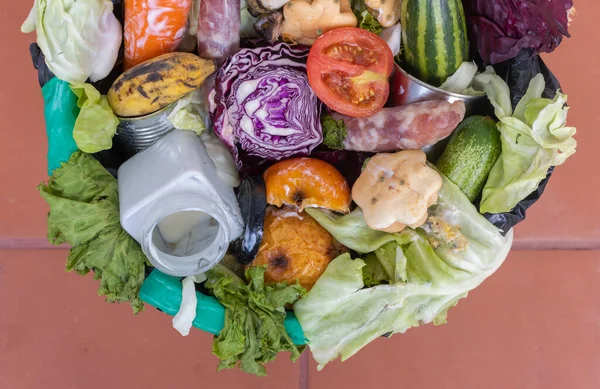 Waste bin with unused food. Food waste as a global problem in the world. Close-up. Isolated on a brown background. Copy space. Food waste concept.