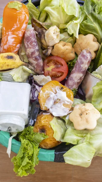 Waste bin with unused food. Food waste as a global problem in the world. Interior. Close-up. Isolated on a brown background. Copy space. Food waste concept.