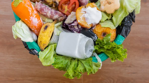 Waste bin with unused food. Food waste as a global problem in the world. Interior. Close-up. Isolated on a brown background. Copy space. Food waste concept.