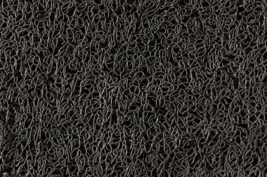 Birbirine kenetlenmiş kıvrımlı şekilleri ve paspası olan koyu bir dokunun görüntüsü