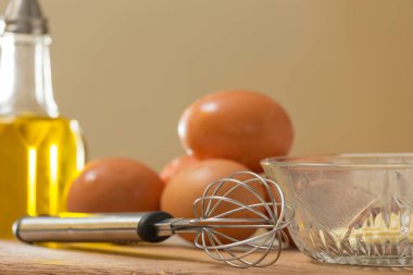 Bir mutfak tahtasına yerleştirilmiş yumurta ve yağlı bir hayat, bir çırpıcı ve mayonez dolu bir kase.