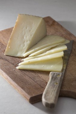 Tahtada peynir kesen bir bıçağın dikey fotoğrafı.