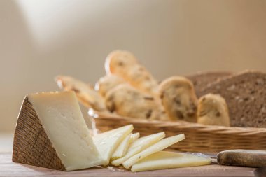 Peynirli kahvaltı hazırlama manzarası, arka planda ekmekli sepet.