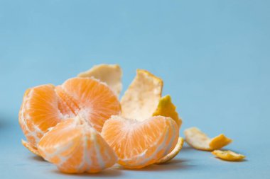 Mandarin soyuldu ve bölümlere ayrıldı, mavi arka planda, sağlıklı turunçgiller.