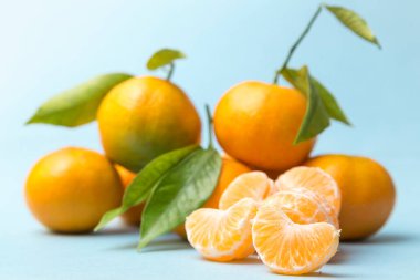 Mandalina seti, biri ön planda soyulmuş, hepsi mavi arka plana yerleştirilmiş.