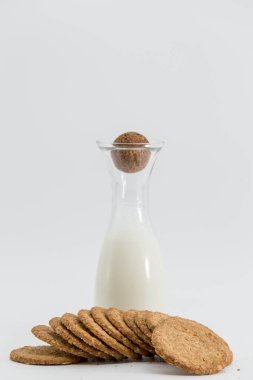 Süt şişesi ve kurabiyeler beyaz arka planda, sağlıklı bir kahvaltıda önlerine düştü.
