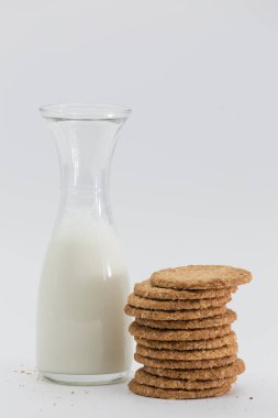 glass bottle with milk and heap of cookies on white background, healthy breakfast