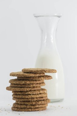 glass bottle full of milk and a bunch of cookies in front, all isolated on white background