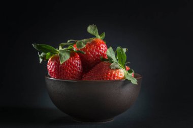 Siyah arka planda çilekli kase, restoran servisi.