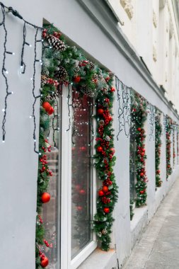 Noel vitrinleri. Firavun çelenk Noel vitrinleri. Kırmızı toplar, böğürtlenler, konilerle süslenmiş ve kırmızı toplar, böğürtlenler, koniler ve ışıklarla aydınlatılmış fidan çelenkleri.