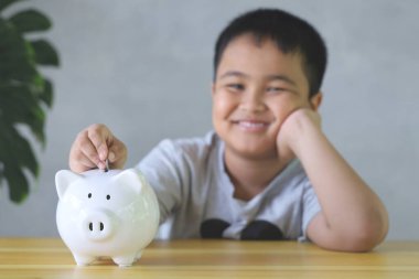 Asyalı çocuk Piggy Bank 'a iyi para koymalar. Para biriktirme kavramı.