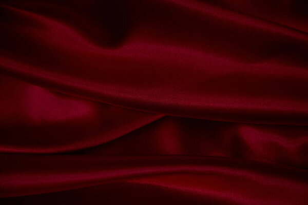 Beautiful draped silk fabric in red. Background from the waves of satin fabric