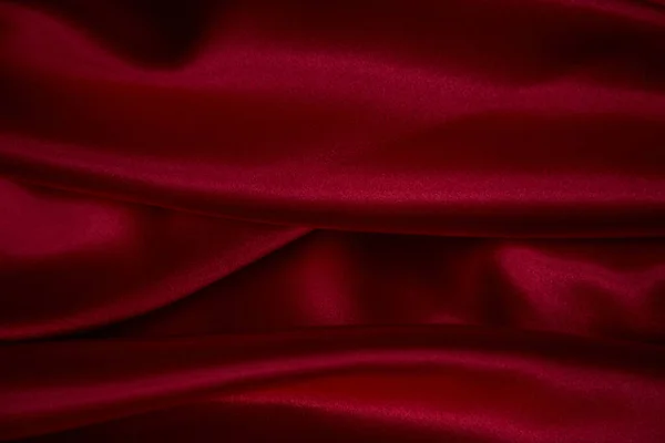 Kırmızıyla örtülmüş güzel ipek kumaş. Saten kumaş dalgalarının arka planı