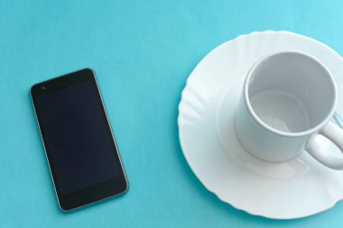 Plakası, cep telefonu ve fincanı mavi arka planda..